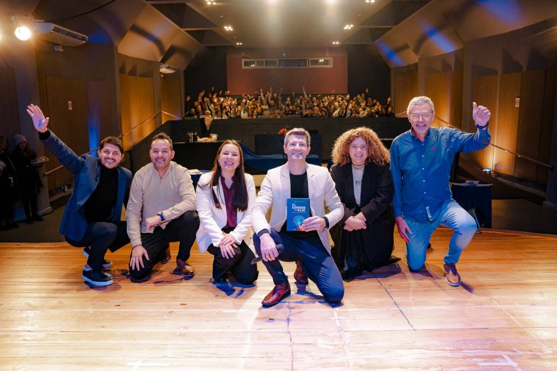 Mauro Chius y los invitados en el escenario, con el libro en la mano y el público de fondo.